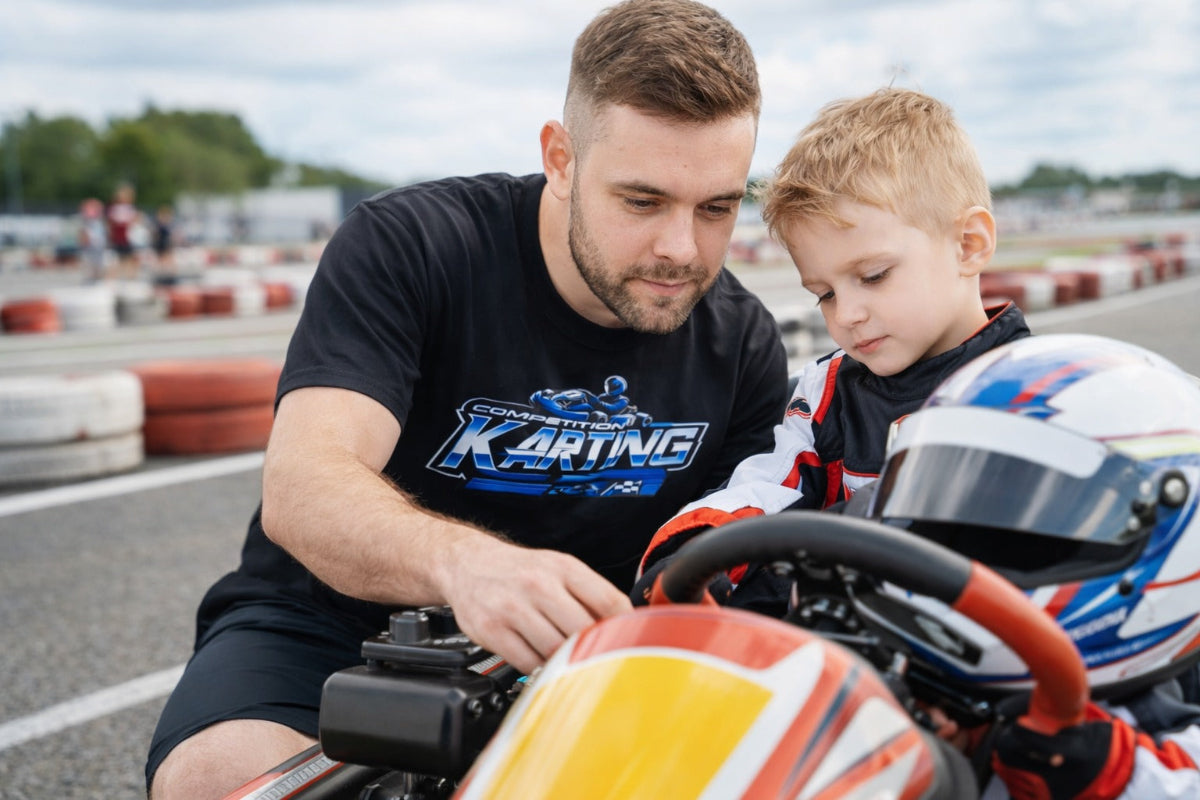 Father wearing Competition Karting shirt helping young driver prepare go kart at karting track