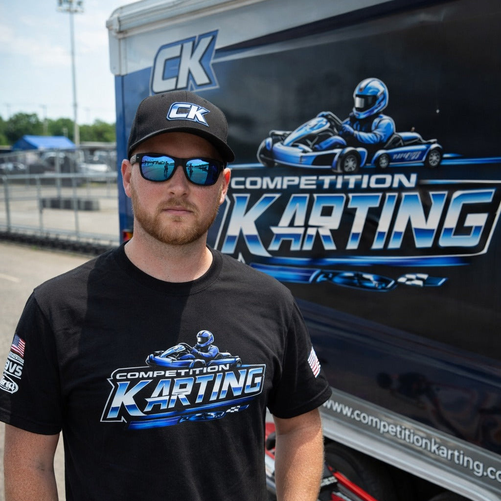 Driver wearing Competition Karting t-shirt standing in paddock beside Competition Karting trailer at kart track-image